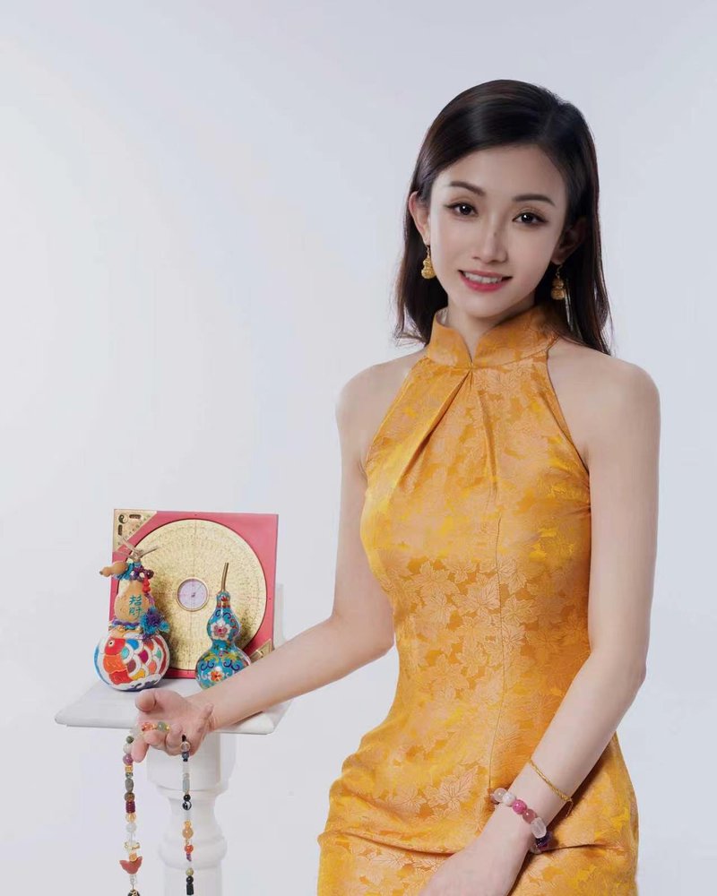 Wendy in a gold qipao beside a luopan compass, gourds and crystal beads